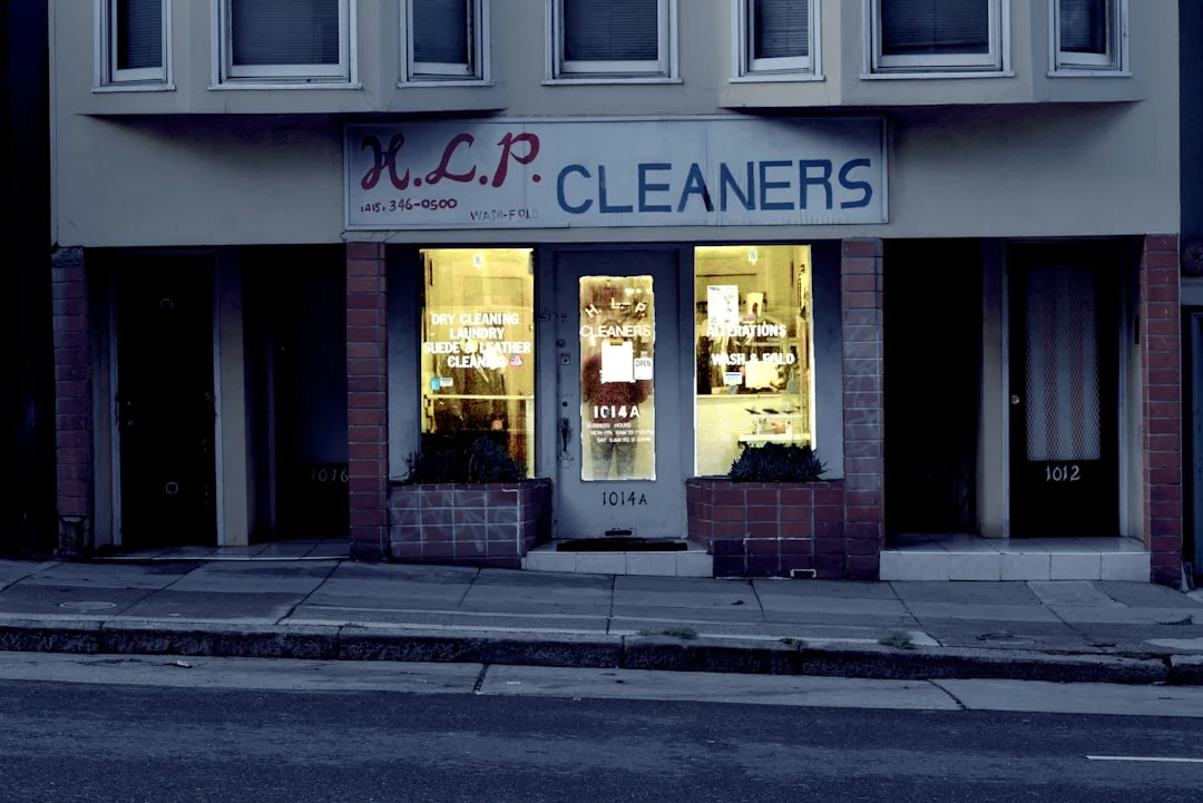 A well-organized utility room with a cordless vacuum, labeled concentrate bottles, microfiber cloths, and a commercial mop bucket on a clean epoxy floor